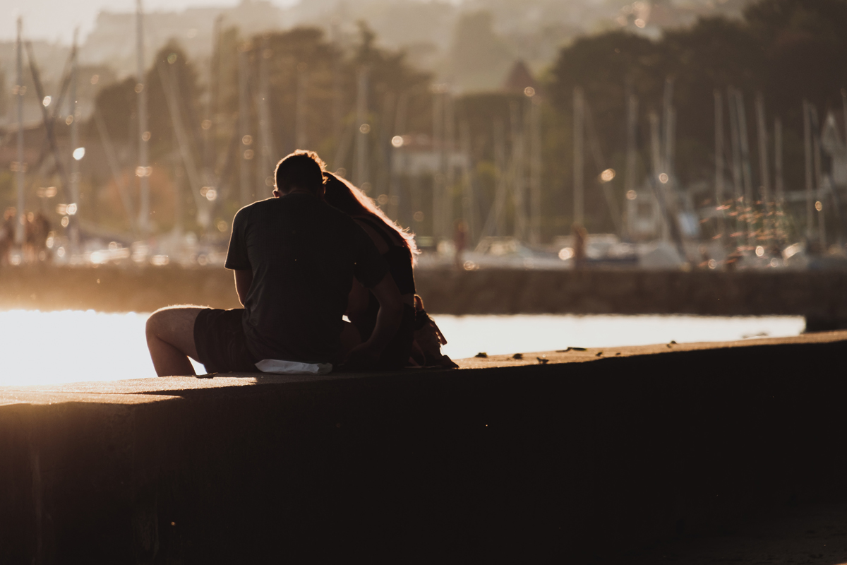 Frau und Mann sitzen am Hafen und genießen den Moment.